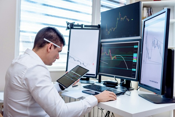 Analyst working at a desk with several monitors