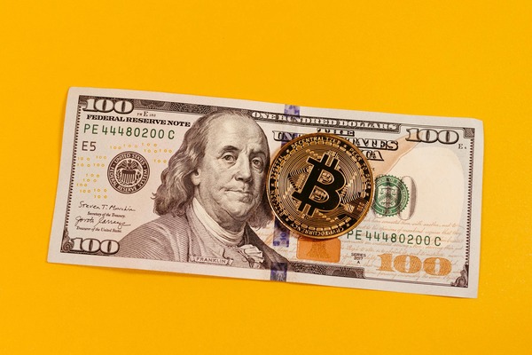 Bitcoin coin on a hundred dollar bill