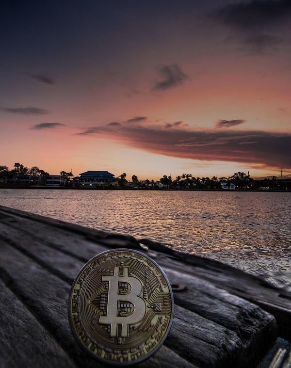 Bitcoin coin on a pier at sunset