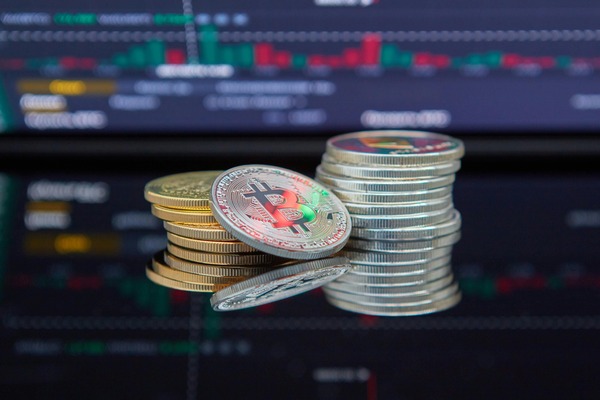 Crypto coin stacks in front of a trading screen
