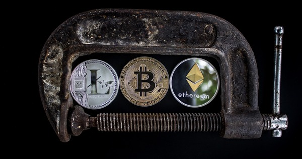 Crypto coins held in a metal clamp