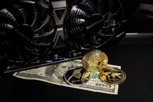 Crypto coins on dollar bills beside a graphics card