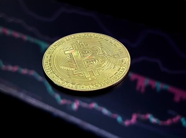 Gold Bitcoin coin over a dark price chart