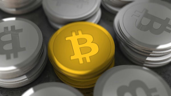 Gold Bitcoin coin stack among silver coins