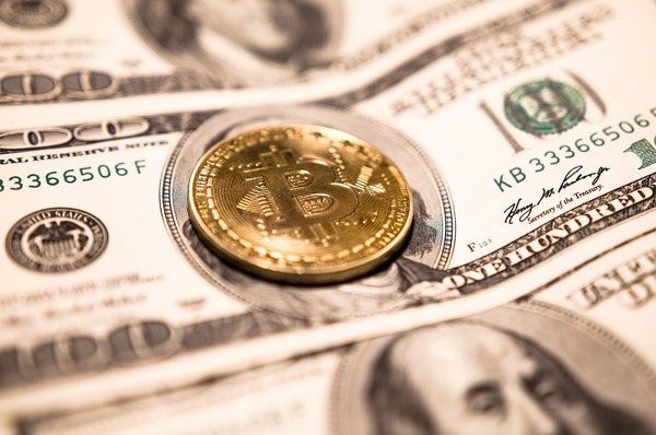 Gold coin on US hundred dollar bills