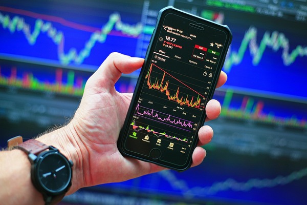 Hand holding a phone with a price chart