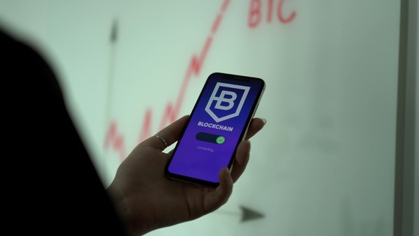Hand holding a smartphone with a blockchain app
