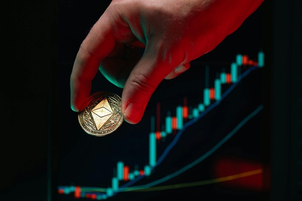 Hand placing a coin on a rising chart