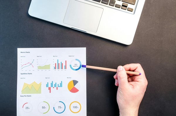 Hand pointing a pencil at financial charts