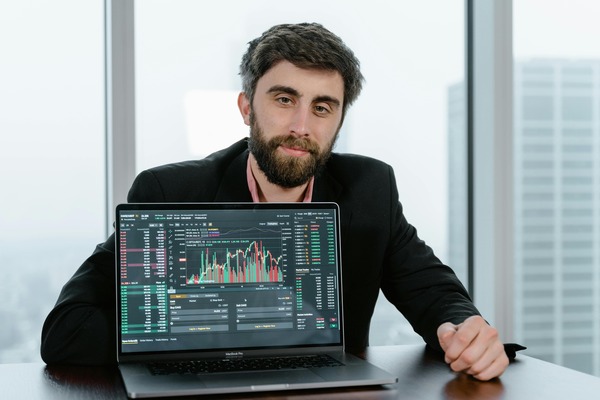Man at a laptop showing trading charts