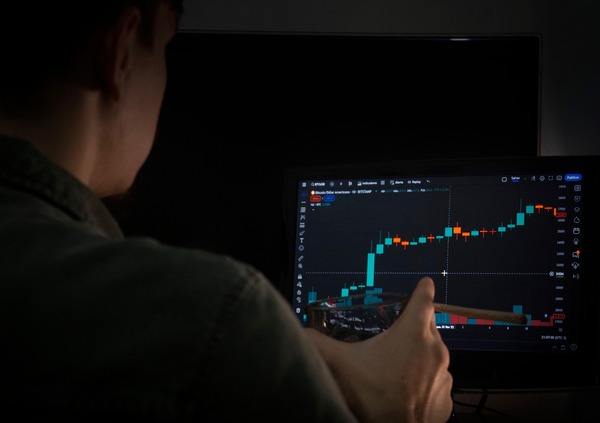Person pointing at a chart on a monitor