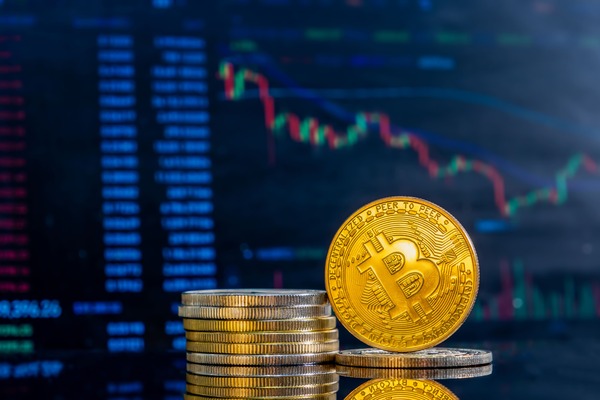 Stack of gold coins in front of a trading chart