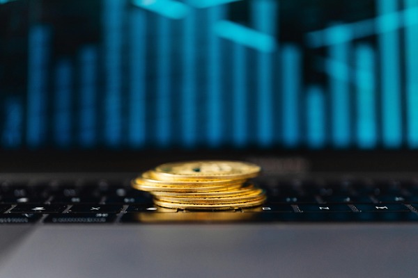 Stack of gold coins in front of blue chart bars