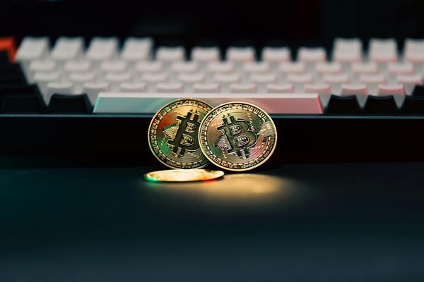 Two Bitcoin coins in front of a keyboard